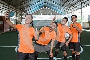 futsal players pose for selfies together using mobile phone cameras
