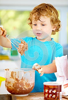 The future of the culinary arts. A little boy covered in dough and flour.