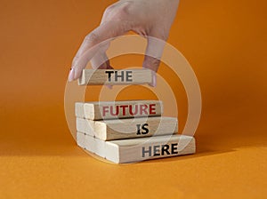 The future is here symbol. Concept words TThe future is here on wooden blocks. Beautiful orange background. Businessman hand. photo