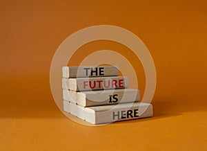 The future is here symbol. Concept words TThe future is here on wooden blocks. Beautiful orange background. Business and The photo