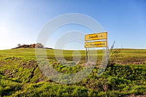 Future and past life road signs in a green field. Text translation: Future - Past