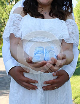 A Future of Love: Embraced Couple Holding Baby Shoes