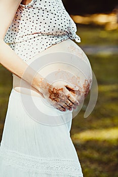 Future mom holds her tummy painted with mehendi