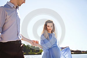 Future mother and father walking near lake holding hands together