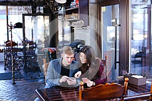 Future parents choosing clothes for child in coffee house with s