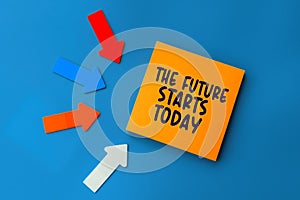 The future starts today - concept of text on sticky note. Orange square sticky note and colorful arrows on blue background, top