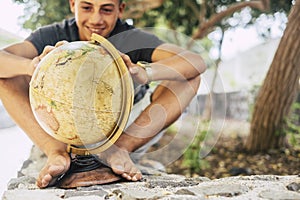 Future of the world with young caucasian teenager loking a globe earth - people and travel lifestyle concept - teenager sit down