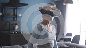 Futuristic girl funny dancing in VR headset for social media platform media in living room at home. Woman avatar