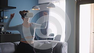 Futuristic girl funny dancing in VR headset for social media platform media in living room at home. Woman avatar