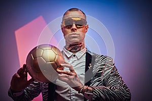 Futuristic guy with golden soccer ball in abstract background