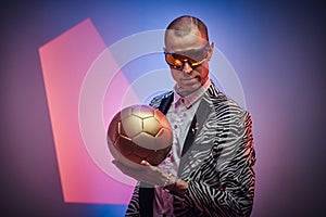 Futuristic guy with golden soccer ball in abstract background