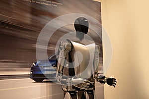 futuristic humanoid robot named Tesla Bot Optimus, designed by Tesla, stands in sleek, modern environment, showcasing advanced