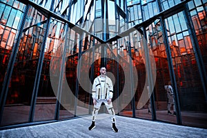 Futuristic man in white clothes stands against the backdrop of a modern building