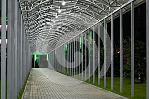 Futuristic pedestrian overpass tunnel with bright lighting, receding into the distance at night. Urban geometry