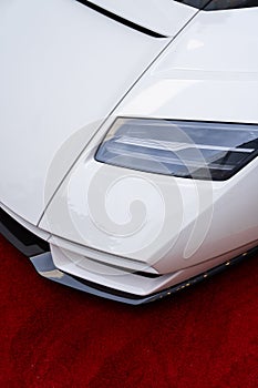 Futuristic shape of powerful headlamp located at front of prestige sports car. White Lamborghini Countach equipped with