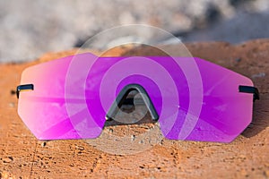 Futuristic sunglasses model rimless with big pink lens reflecting the sun in a summer day closeup. Selective focus