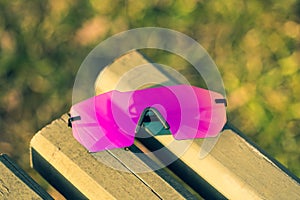 Futuristic sunglasses model rimless with big pink lens reflecting the sun in a summer day closeup. Selective focus