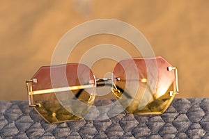 Futuristic sunglasses rimless design with pink lenses and golden frame shoot outside in a sunny day. Selective Focus