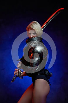 Futuristic woman with cybernetic hand and sword in dark background