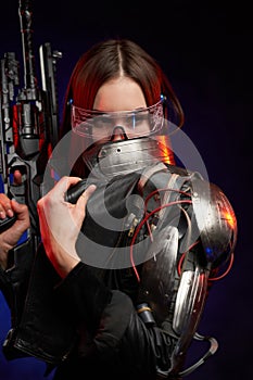 Futuristic woman with eyewear and rifle in dark blue background