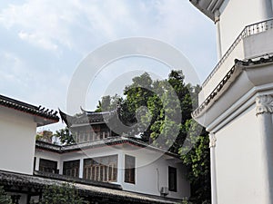 Fuzhou - A white building in Chinese style build in Fuzhou, China. There are dense trees behind the building. Overcast