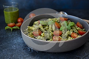 Fuzzily Italian pasta with pesto on black concrete background.