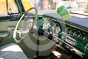 Fuzzy dice hanging from the mirror in a classic American car