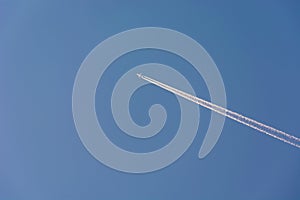 A fuzzy high-flying passenger plane and white streaks on a sky