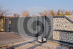 Gabion. Automatic entrance gate used in combination with a wall made of gabion photo