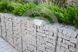 Gabion fence with stones in wire mesh and outdoor lighting. Gabion wire mesh fencing with natural stones