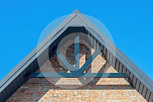 The gable of a brick house, the construction of a roof with decorative beams