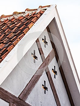 Gable of an old historical house with tiles, wooden details and crosses