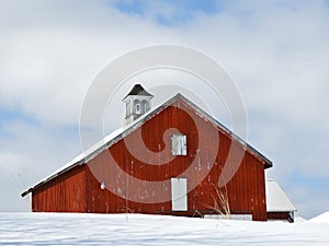 Gable roof vintage red barn with cupola in country