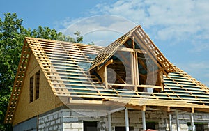 Gable roofing construction and framing. An incomplete concrete block house construction with timber roof framing installed over