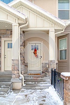 Gabled home entrance with snowy wet steps leading to the glass paned front door