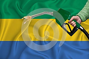 GABON flag Close-up shot on waving background texture with Fuel pump nozzle in hand. The concept of design solutions. 3d rendering