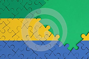 Gabon flag is depicted on a completed jigsaw puzzle with free green copy space on the right side