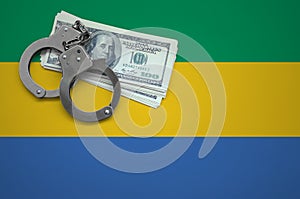 Gabon flag with handcuffs and a bundle of dollars. The concept of breaking the law and thieves crimes