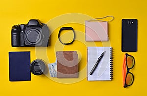 Gadgets and accessories layout on a yellow background. Power bank, photographic equipment, purse with dollars, smart clock