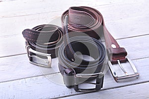 Gadgets and accessories for men on light wooden background. Fashionable men s belt, wallet, lighter, Stainless hip flask