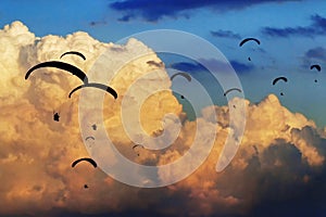 Gaggle of paragliders fly with giant clouds on the background