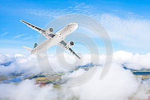 A gaining passenger plane flies above the clouds and forest landscape