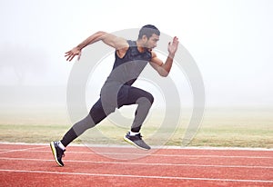Gaining some serious speed. Full length shot of a handsome young male athlete running on an outdoor track.