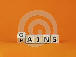 Gains and pains symbol. Turned wooden cubes, changed word pains to gains. Beautiful orange background. Business, pains and gains