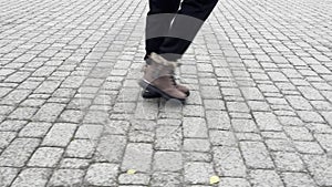 The gait of a woman whose feet are shod in warm shoes. She walks along a cobblestone road