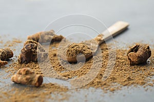 Galangal root and galanga powder in wooden spoon on rustic table