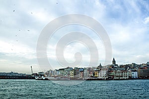 Galata Tower, on its hill, in Karakoy and Beyoglu district, taken during a winter afternoon, while the sea and ships can be seen