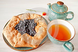 Galeta galette tart cake pie of whole grain flour with blueberries on a white country table with Turquoise color cup with flowers