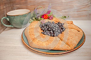 Galeta galette tart cake pie of whole grain flour with blueberries on a white country table with Turquoise color cup with flowers