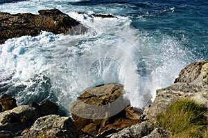 Waves splashing against the rocks. Blue sea with white foam, Galicia, Spain.